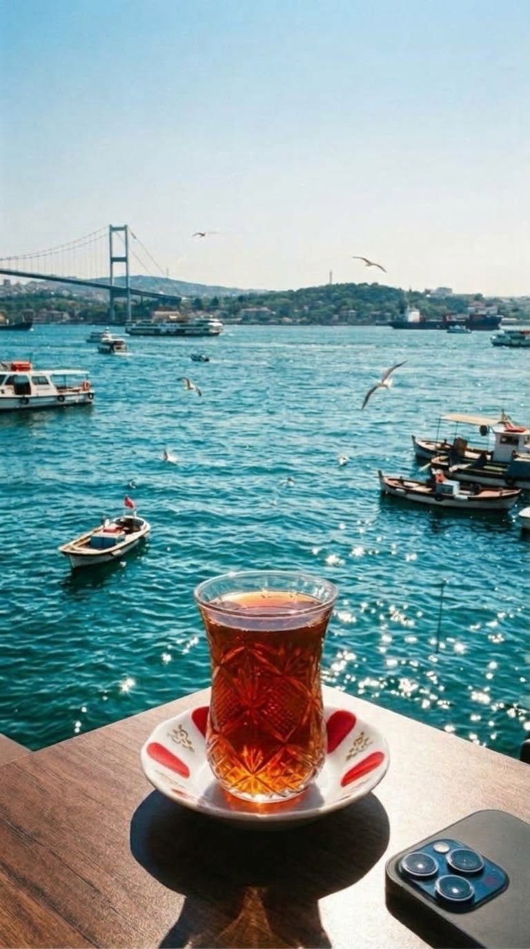 a turkish tea glass on a café table by the bosphorus, a phone lying face down beside it
